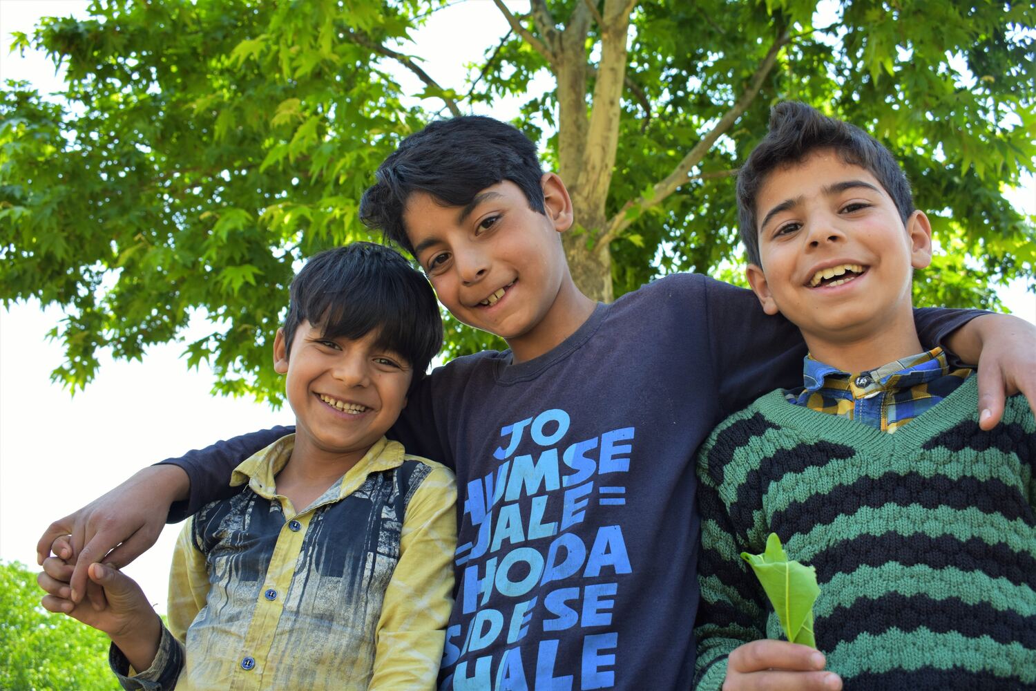 Three boys smiling together outdoors